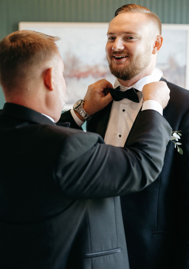 Groom having bowtie adjusted for wedding day